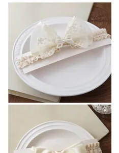Détail d'un bandeau pour bébé en dentelle avec nœud en tulle et perles sur plat blanc