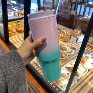Close-up of pink and green gradient 30oz insulated tumbler held in a hand