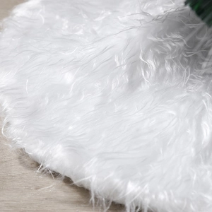 Plush white faux fur Christmas tree skirt on light wood floor with soft texture