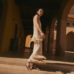 Abito lungo in maglia beige senza maniche con dettagli di frange a strati e nappe retrò