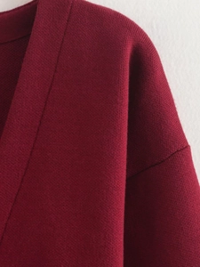 Detaillierte Nahaufnahme des V-Ausschnitts und Strickmusters am weinroten Cardigan