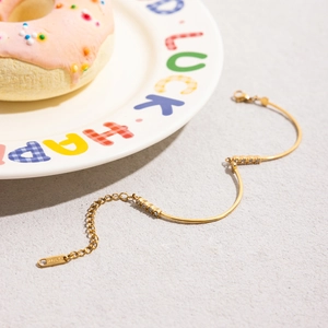Detailed shot of 18K gold stainless steel bracelet with white diamonds on a ceramic plate