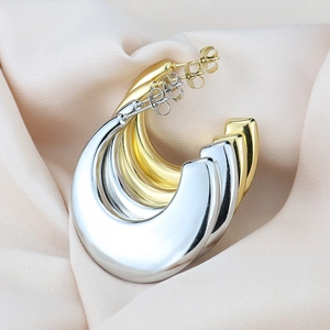 Macro shot of chunky water-drop earrings in gold and silver finish on silk fabric