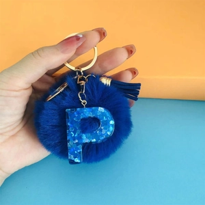 Detail of blue pompom keychain with sequined letter P and matching blue tassel charm