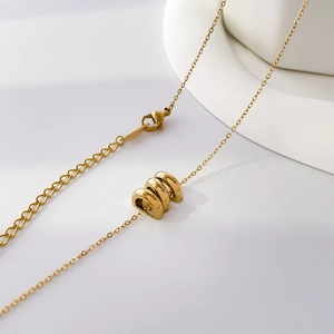 Macro view of gold triple ring pendant necklace with adjustable chain and lobster clasp