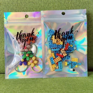 Holographic thank you bags filled with colorful hair ties and building blocks on green fabric