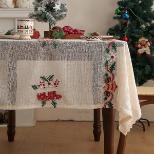 Detail of Christmas tablecloth with embroidered stockings and bells on white lace mesh
