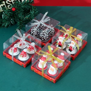 Top view of 4 Christmas candle gift boxes with Santa and pinecone shapes on green background