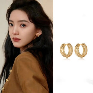 Detail of gold quilted hoop earrings featuring a close-up texture and on-model display