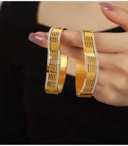Detail of gold-tone hollow floral chain bangle with geometric patterns and diamond accents