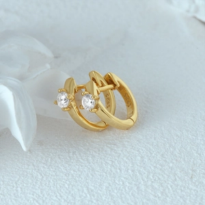 Macro view of gold S925 sterling silver huggie earrings with round diamond accents
