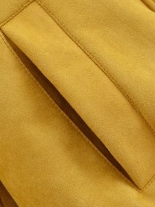 Detailed close-up of mustard yellow faux suede fabric with precise stitching on jacket