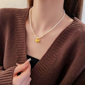 Close-up of pearl necklace with golden lucky bag pendant on neck, vintage style