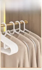 Close-up of white curved non-slip plastic hangers protecting clothes from shoulder bumps