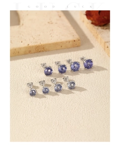 Detailed macro shot of blue-purple gemstone earrings in various sizes on stone surface