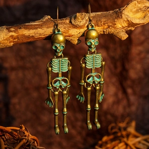 Detail of vintage bronze skull earrings with green patina hanging on a rustic wood branch