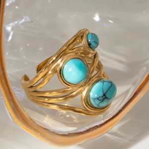 Macro detail of gold-plated multi-layer ring featuring three turquoise blue stones