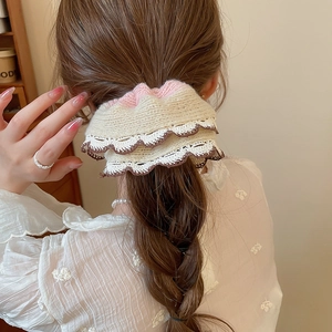 Detail of cream knitted scrunchie with pink lace edges worn on a low ponytail