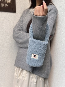 Blue plush bottle sleeve with black cat patch shown on a model with grey sweater