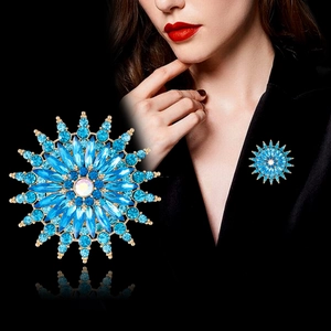 Detail of blue snowflake brooch with multi-faceted crystals on a black suit lapel