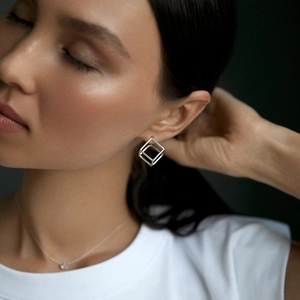 Minimalist S925 sterling silver geometric cube earrings on model with dark background