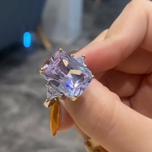 Elegant gold ring featuring a large radiant cut lavender stone and triangle side diamonds