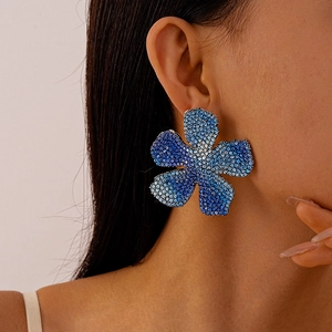 Detail of oversized flower earring featuring blue gradient rhinestones on a model