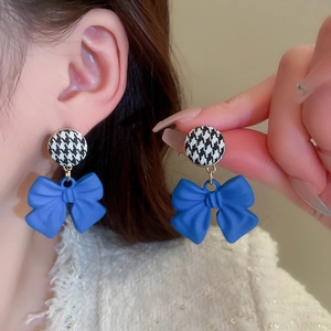Detailed close-up of blue bow earrings with houndstock pattern studs in a French vintage style