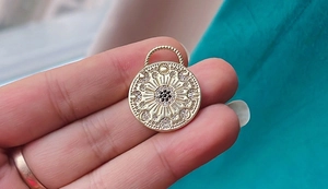 Macro view of a gold sunburst pendant featuring a black center stone and clear zircons