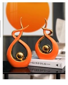 Close-up of modern ceramic sculptures in orange and gold with smooth abstract lines