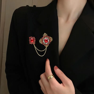 Elegant gold-tone ballet dancer brooch with red crystals and pearls on a black blazer