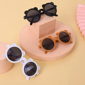 Round bear ear children's sunglasses in black, brown, and white on geometric pedestals