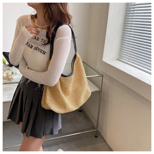 Women's woven tote bag with beige straw texture and black leather strap detail