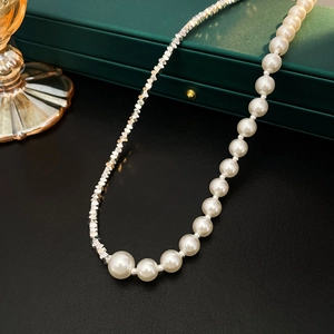 Detail of elegant silver beads and white pearl necklace on a dark green jewelry box