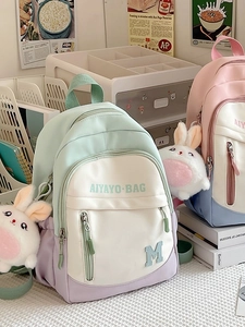Pastel colorblock school backpack for girls with rabbit plush charm on a study desk