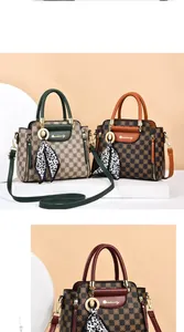 Macro view of checkerboard pattern leather with silk scarf detail on top handle bag