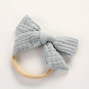 Détail d'un nœud en coton mousseline bleu clair avec bandeau élastique beige pour bébé