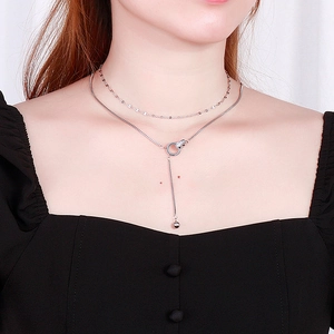 Close-up of double-layered silver necklace with rhinestone circle and tassel pendant