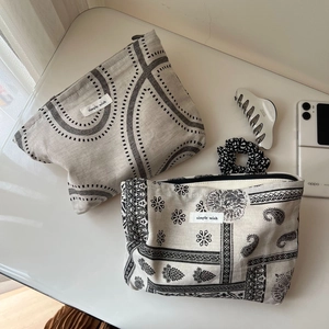 Flat lay of linen makeup bags with geometric and floral prints beside a smartphone