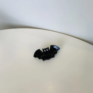 Macro shot of a black acrylic bat hair claw clip with glitter finish and white eyes