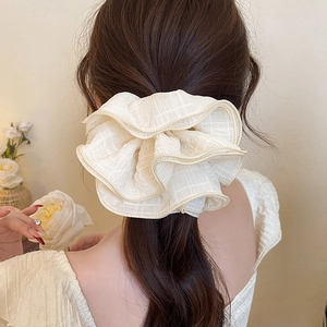 Détail d'un grand chouchou crème avec motif à carreaux sur une coiffure en queue de cheval