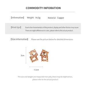 Vue détaillée de boucles d'oreilles géométriques creuses dorées avec incrustation de zircon