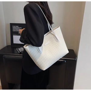Chic cream tote bag with woven texture and slim handles shown in a lifestyle setting