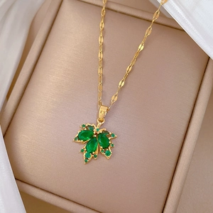 Macro shot of maple leaf pendant with green gemstone in a luxury jewelry gift box