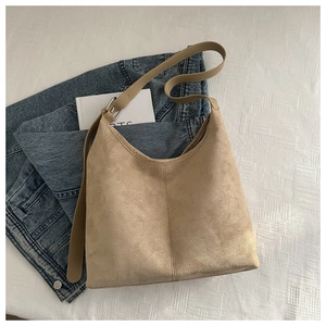 Detail of sandy khaki suede hobo bag with adjustable strap on white woven background