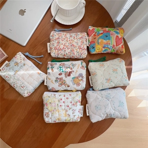 Close-up of floral quilted cotton coin purses with zipper and lanyard on a wooden desk