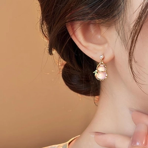 Detail of pink cat-eye stone gourd earring with a white pearl and green leaf accent