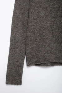 Detailansicht des dunkelbraunen Strickpullovers mit Rippensaum und Wollstruktur