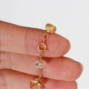 Macro shot of 18k gold-plated oval jump ring connecting yellow stones on a fine chain