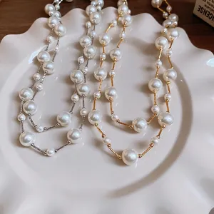 Elegant gold and silver pearl sweater necklaces displayed on a decorative ceramic plate